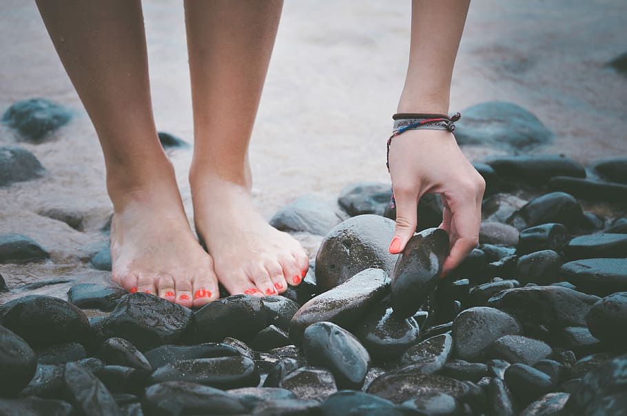 person picking a black wet stone, person holding black rock, beach HD wallpaper
