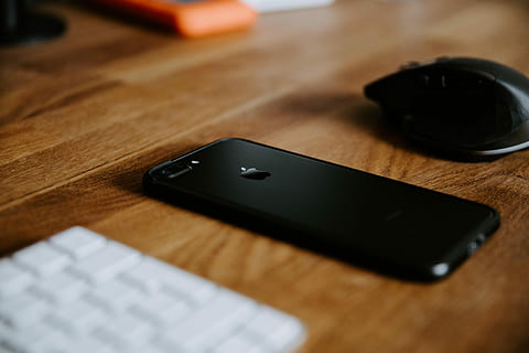 black iPhone 7 Plus on brown wooden table near black wireless computer mouse HD wallpaper
