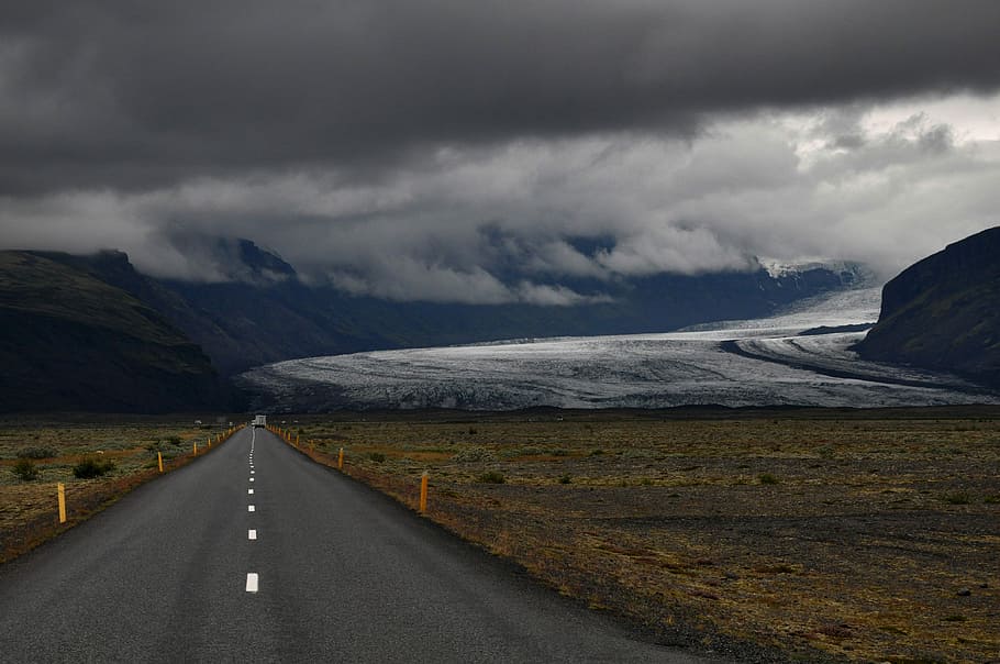 grey asphalt road under dark cloudy sky, grey road leading to mountain HD wallpaper