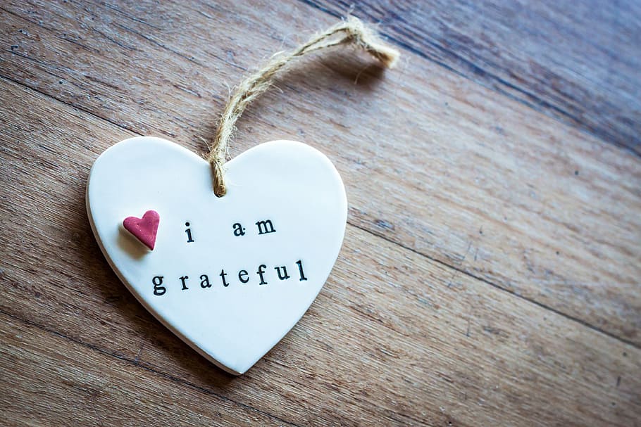 heart-shaped keychain with i am grateful text overlay, wooden
