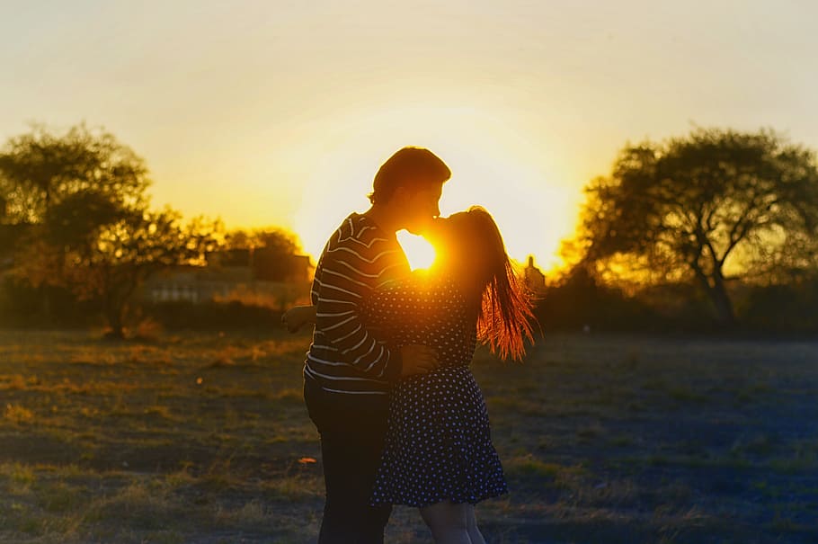 silhouette photography of couple kissing in the middle of the field, couple kissing on grass field during sunset