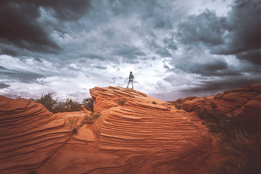 person standing on brown rock formation during daytime, person standing on top of canyon HD wallpaper