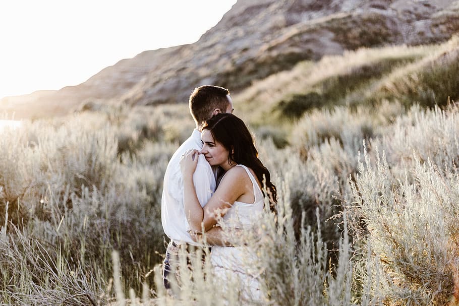 man hugging woman near mountain, couple stands beside grass, women HD wallpaper