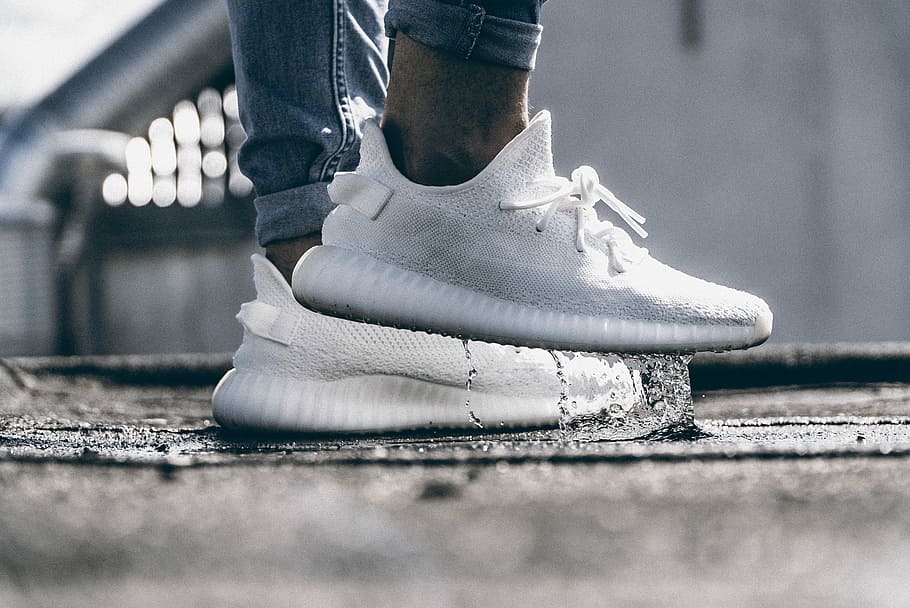 person wearing pair of cream white Adidas Yeezy Boost 350 shoes, person wearing cream white adidas yeezy boost 350 V2 standing on water