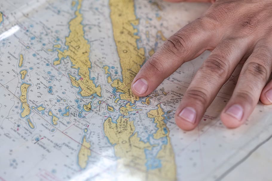 person holding blue and green map, person touching white and yellow map HD wallpaper