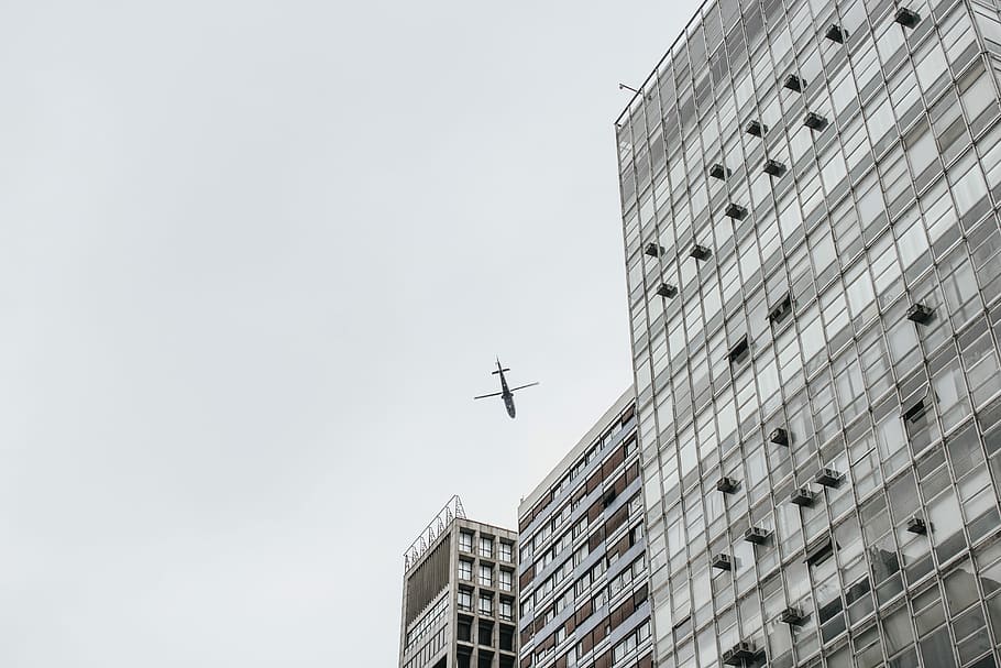 low-angle photography of airliner and high-rise buildings, low-angle photography of flying plane near building at daytime HD wallpaper
