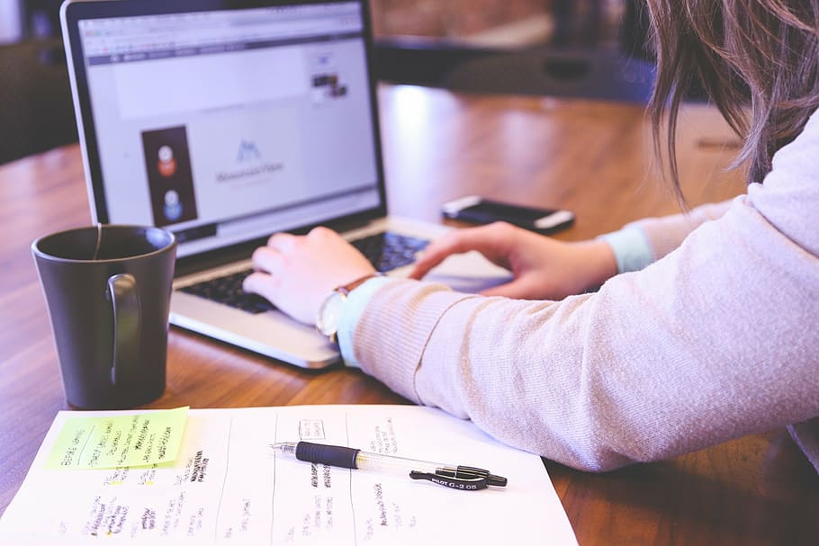 woman using MacBook Pro beside mug and smartphone, student HD wallpaper