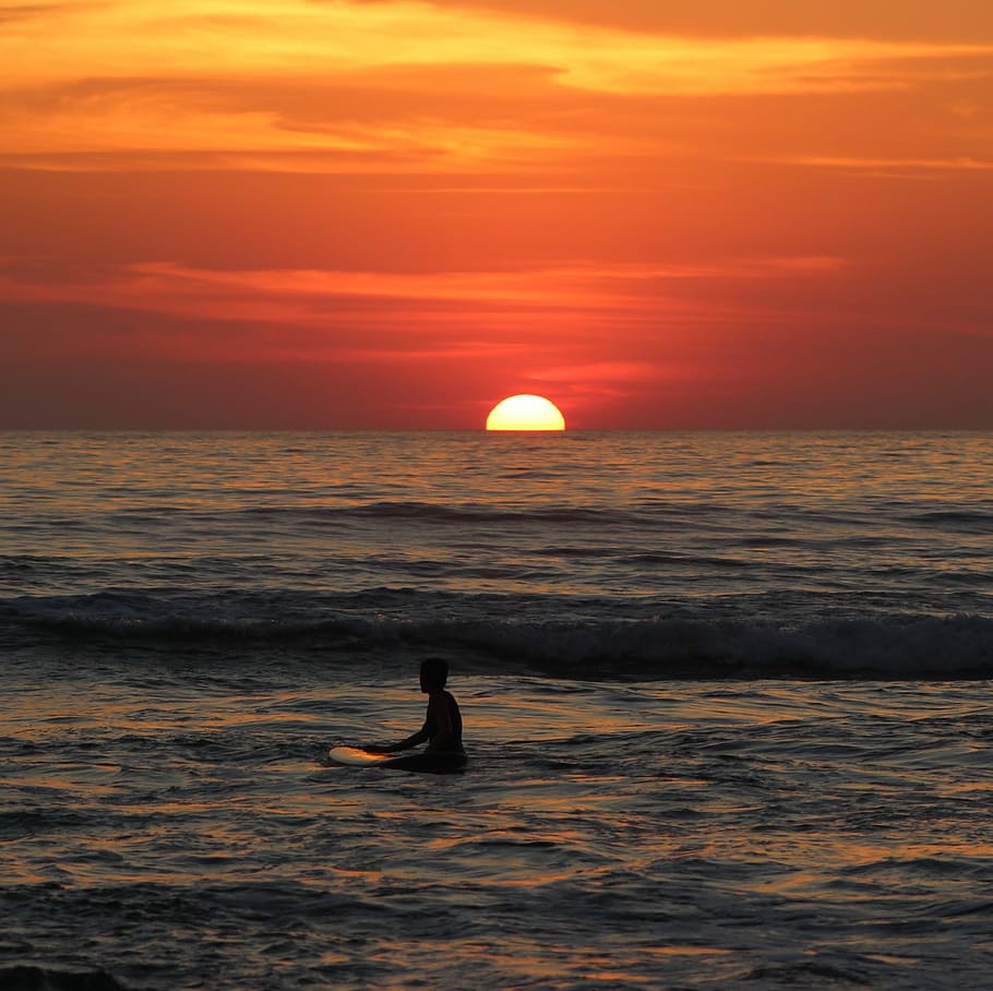 man on body of water during sunset, man on surfing board floating on water at golden hour HD wallpaper