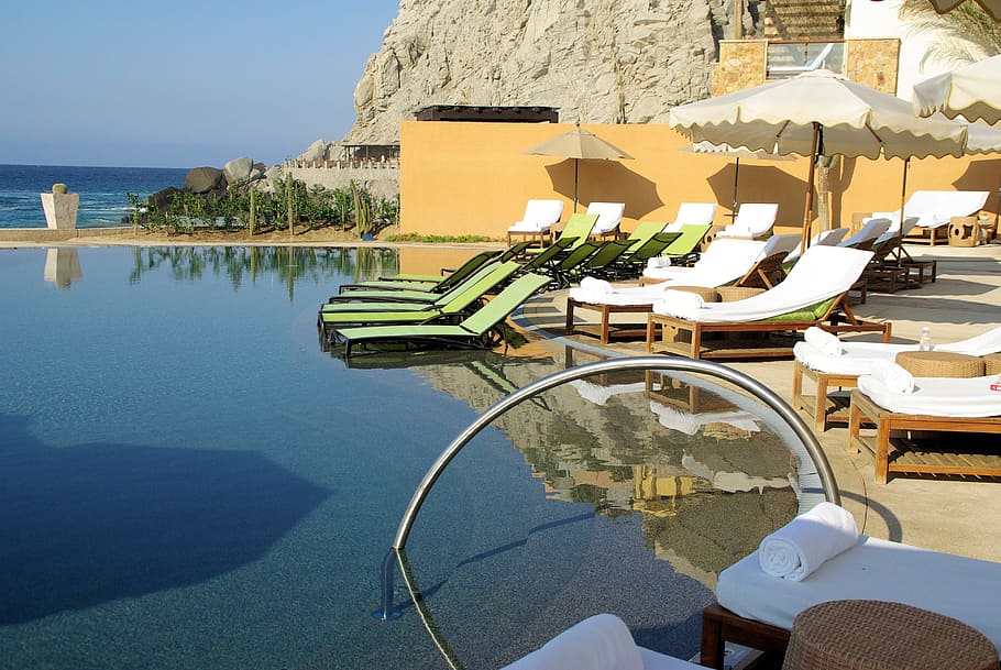 empty white and green padded loungers facing body of water, Cabo, San Lucas, Mexico