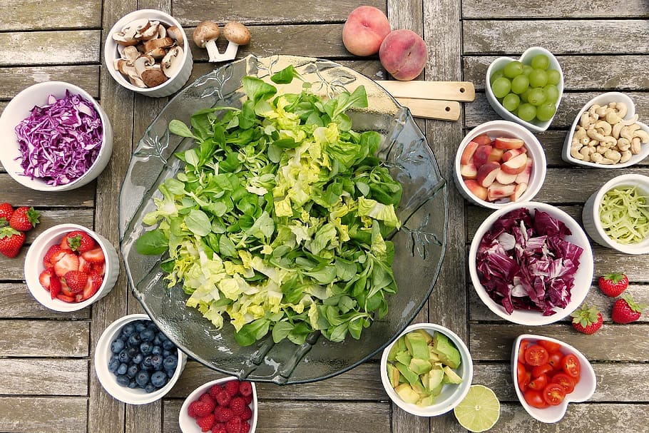 sliced vegetables and fruits on bowls, salad, berries, nuts, avocado