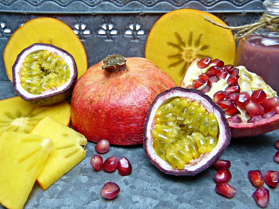 sliced pomegranate on grey surface, pomegranate seeds, passion fruit
