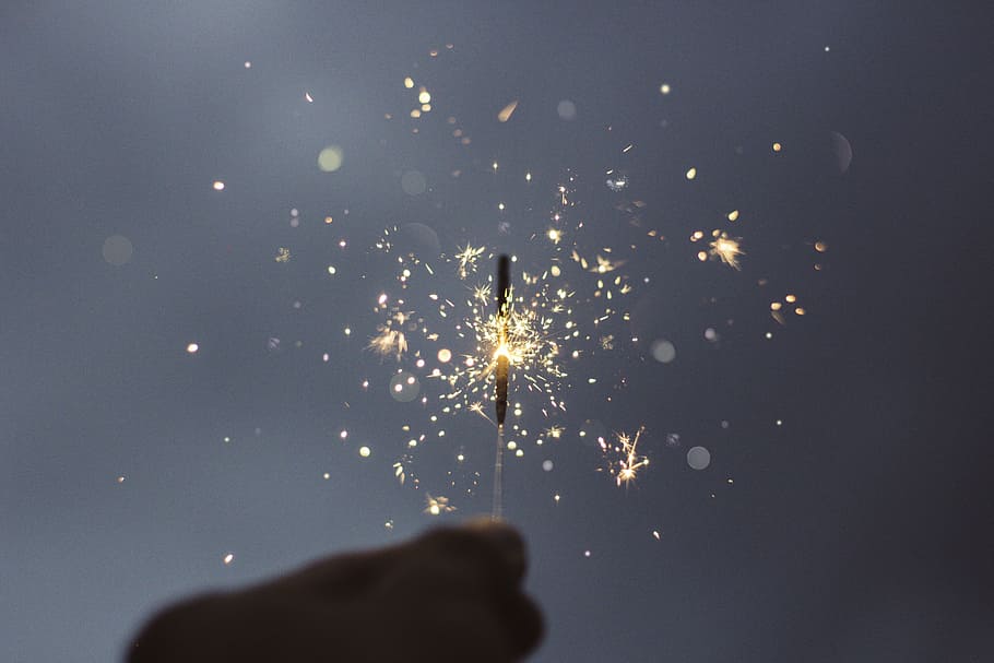person holding lighted sparklers, person holding sparkle firecracker in auto focus photography HD wallpaper