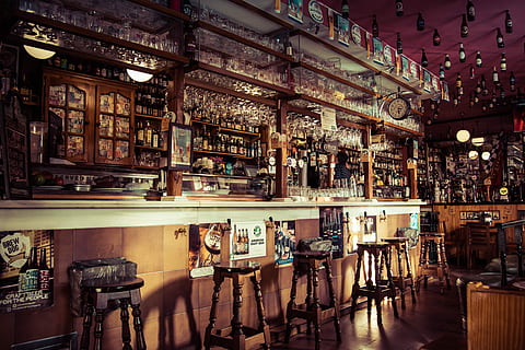 The interior of a bar with stools, glass cups and empty bottles attached to the roof in Madrid, bar interior HD wallpaper