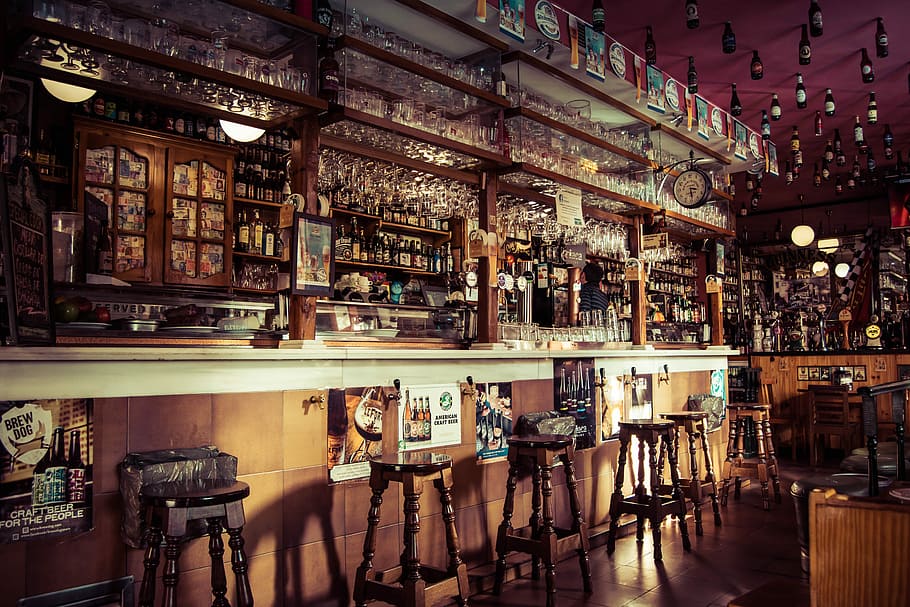 The interior of a bar with stools, glass cups and empty bottles attached to the roof in Madrid, bar interior HD wallpaper