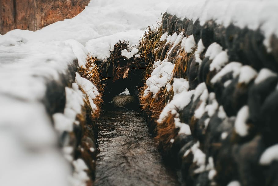 pathway between stack of hay with snows, focus photography of canal HD wallpaper