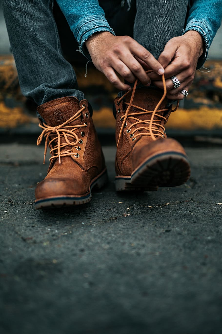 photography of person lacing his/her boots, person holding shoe lace