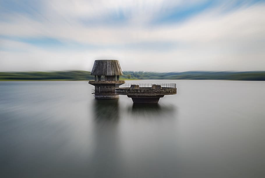 house near river, brown shed at the middle of the ocean during day time HD wallpaper