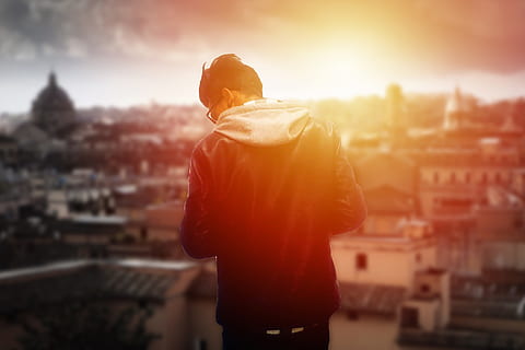 selective focus of man standing front of houses and building during golden hour HD wallpaper