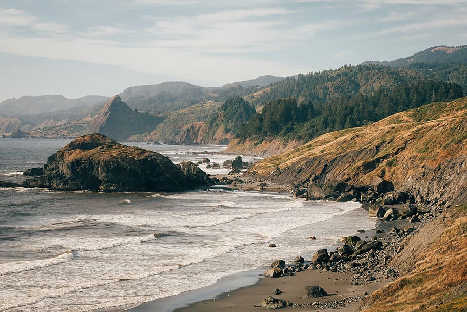 island covered in tree near sea, ocean waves hitting the foot of the cliffs HD wallpaper