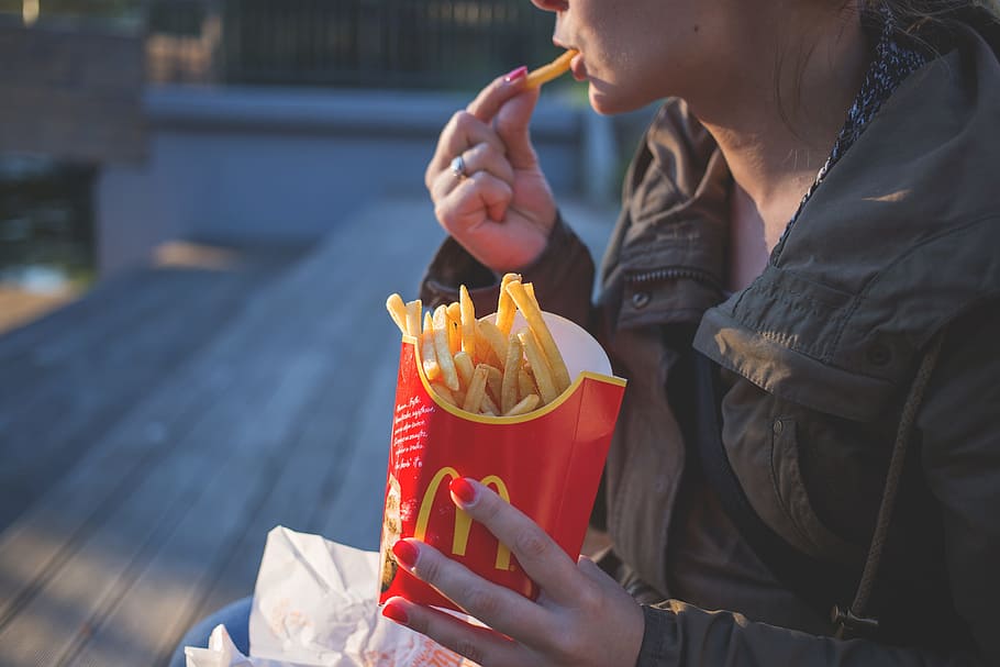 tilt-shift lens photo of woman sitting on a bench eating McDonald's fries, HD wallpaper