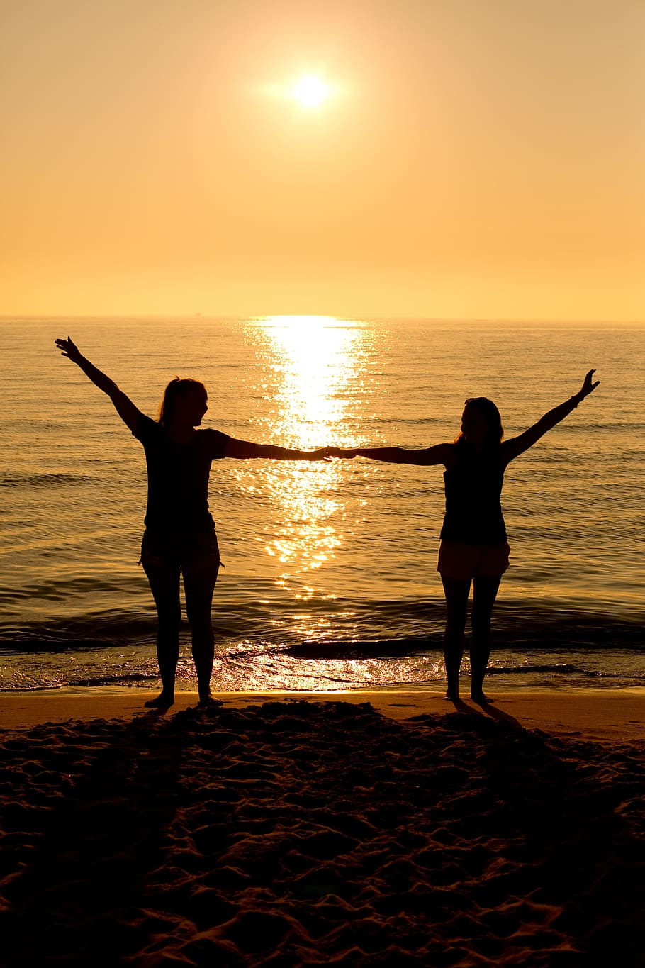 silhouette of two persons holding each others hand on beach HD wallpaper