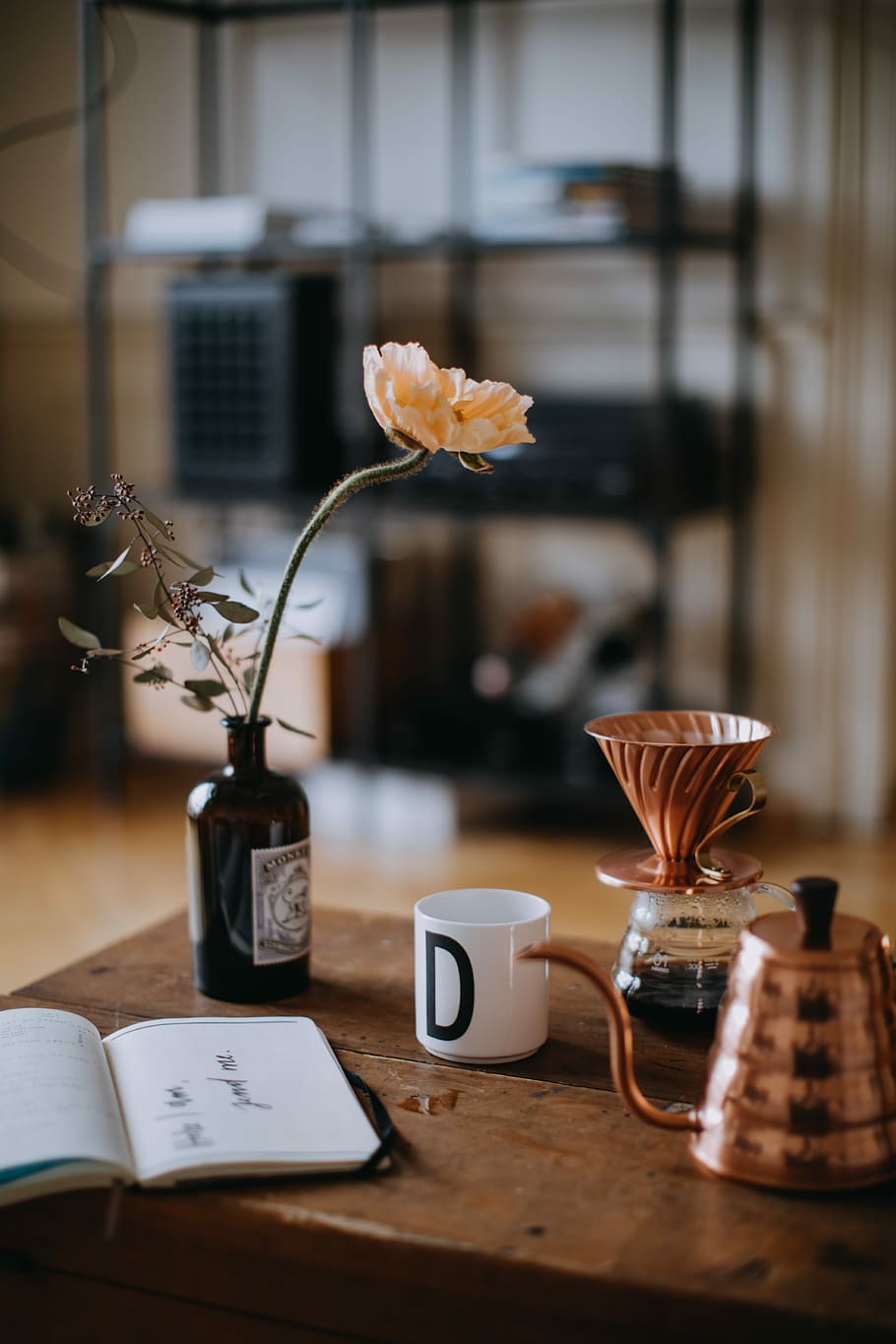 orange petaled flower on vase, selective focus photography of opened book beside black flower vase and mug HD wallpaper