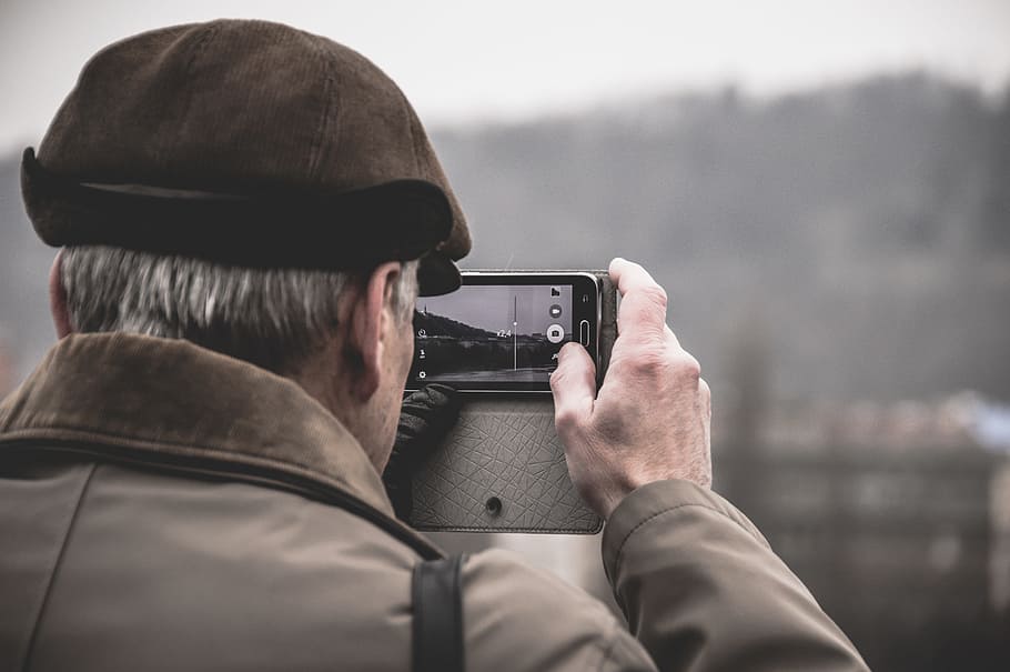 photo of man taking photo using camera, man holding camera taking photo of building at daytime HD wallpaper