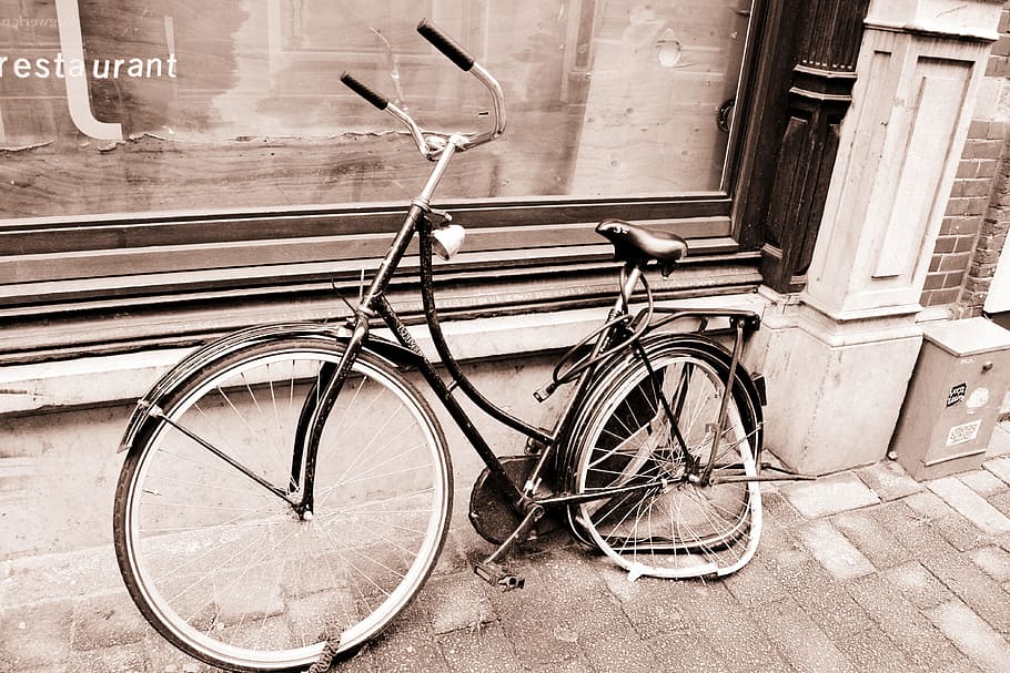 step-through frame bike with broken wheel parked on side on pavement