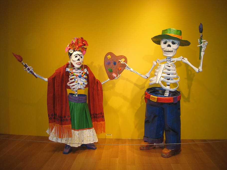 man and woman skeleton decors near yellow painted wall, day of the dead