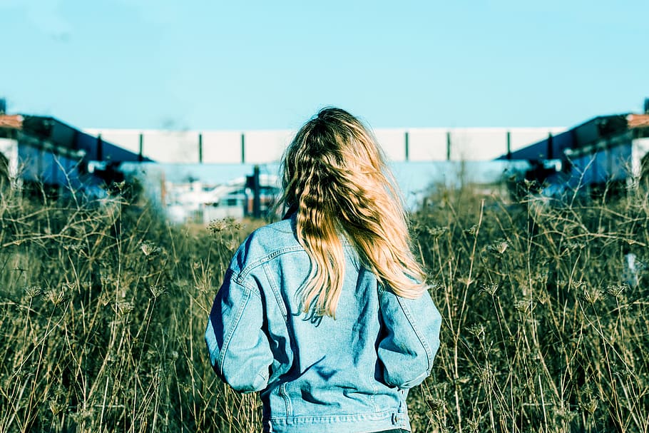 woman wearing blue denim jacket standing on grass field, shallow focus photography of woman back, HD wallpaper