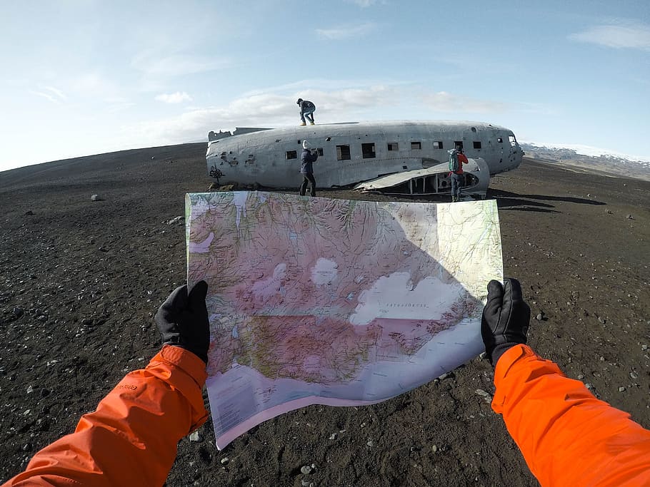 world map on hand, person holding map with view of three people standing on wrecked plane on ground HD wallpaper