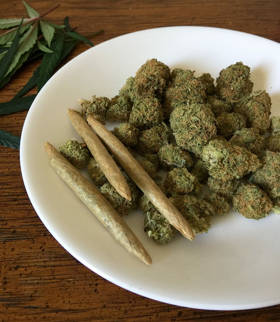 green kush in round white ceramic plate on top of brown wooden table