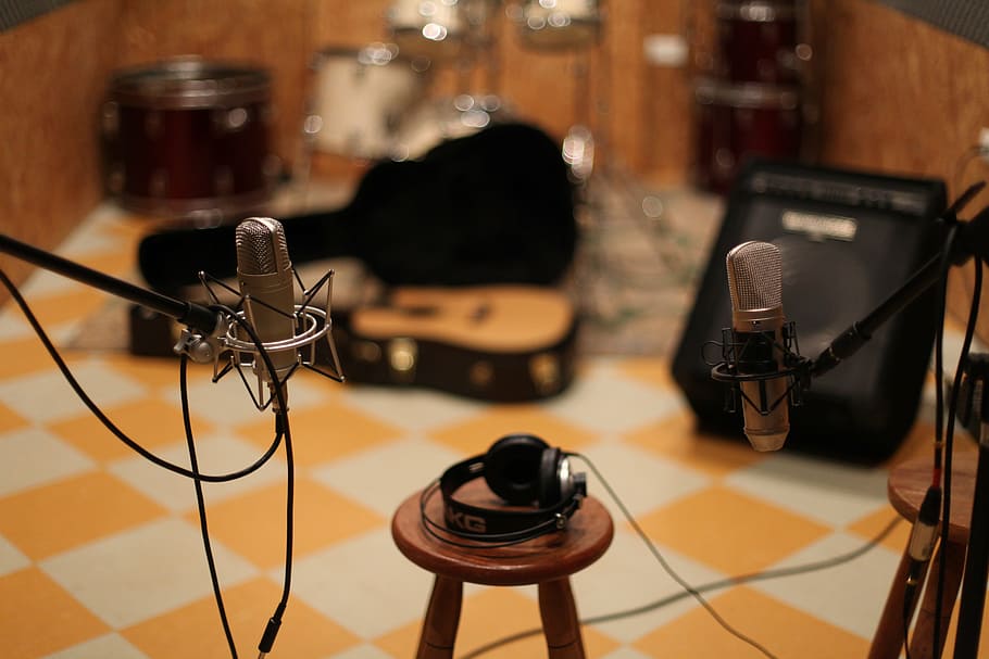 shallow focus photography of black headphones on brown wooden bar stool chair between microphones with stands HD wallpaper