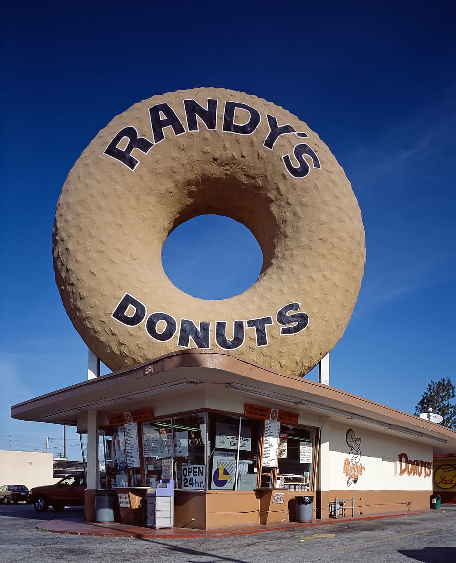 person taking photo of Randy's Donuts store at daytime, doughnut