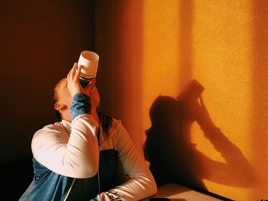person in white and blue jacket drinking during orange sunset, woman drinking on a cup HD wallpaper