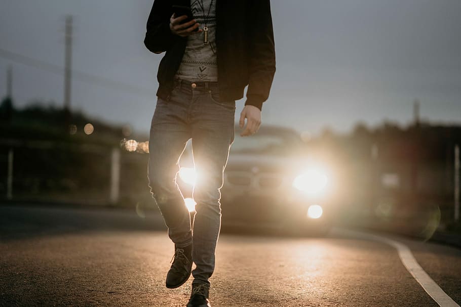 man in black jacket walking on street, person holding smartphone while walking HD wallpaper