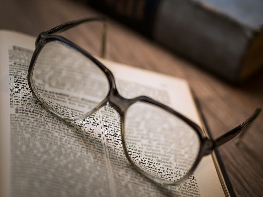 black framed eyeglasses on top of bookpage, knowledge, library