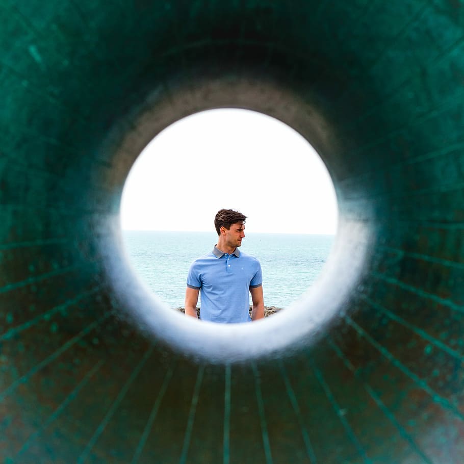 man in blue polo shirt standing distance with ocean during daytime HD wallpaper