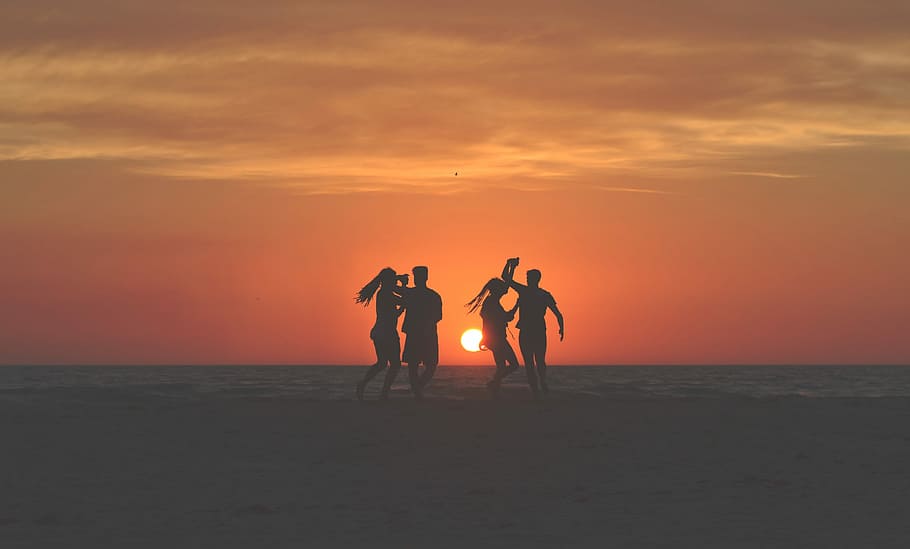 silhouette photo of four people dancing on sands near shoreline, silhouette of four person on beach shore under orange sunset HD wallpaper