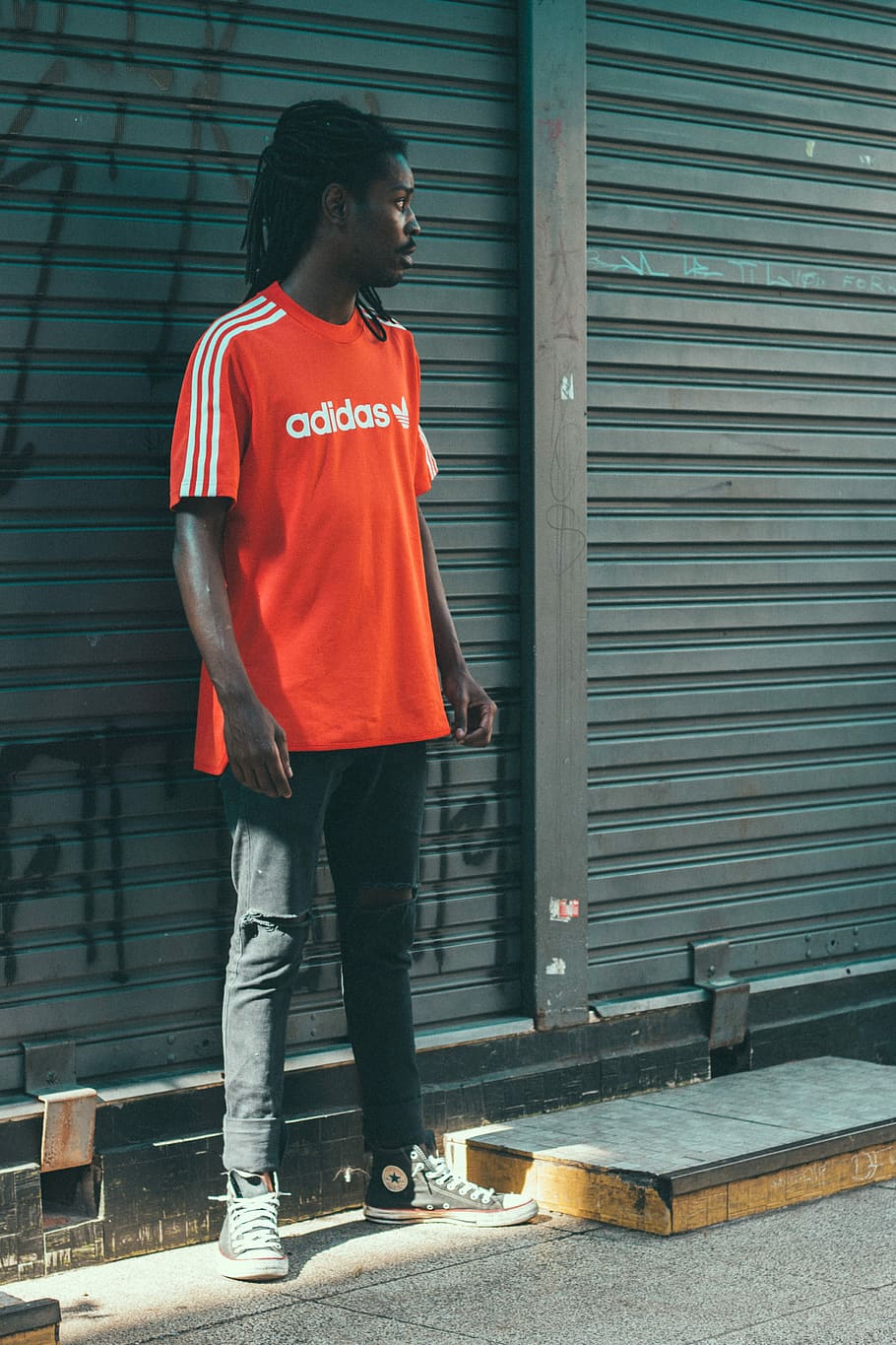 man wearing red Adidas t-shirt in front of roller shutter, man weaing adidas shirt standing near the roller shutter, HD wallpaper