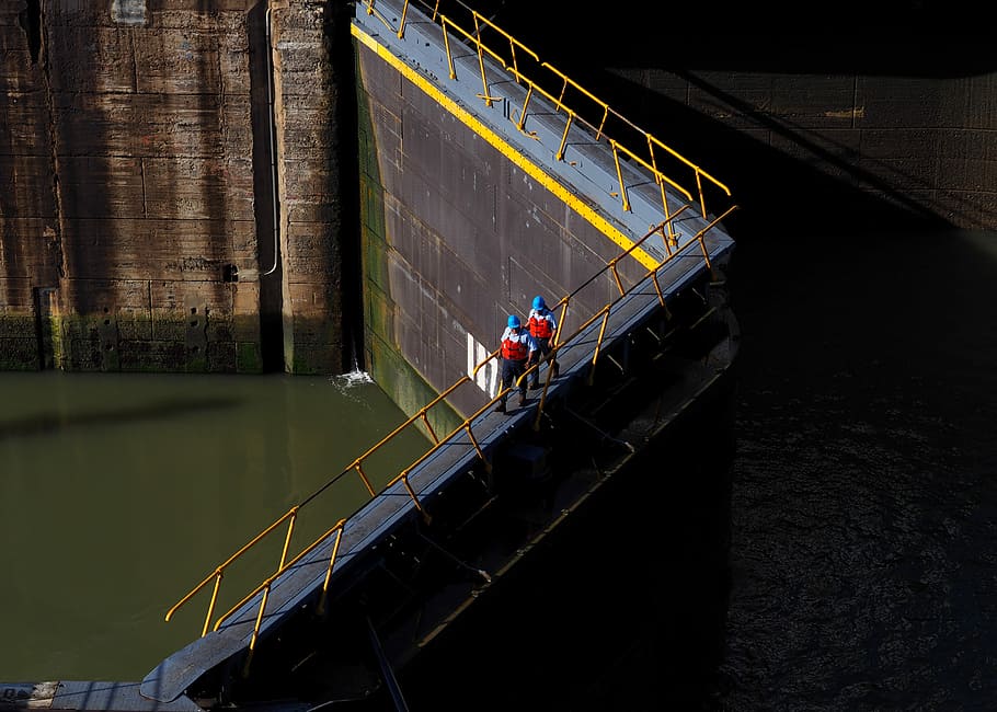 two persons walking on bridge, two persons walking between guardrails at daytime HD wallpaper