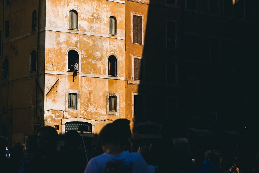 person sitting on building window, people gathering near building HD wallpaper