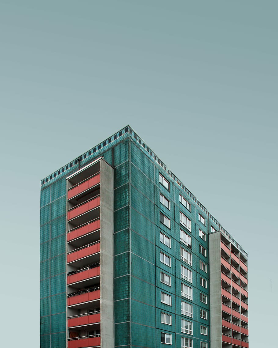 blue and white building under dark clouds, teal and red concrete structure HD wallpaper