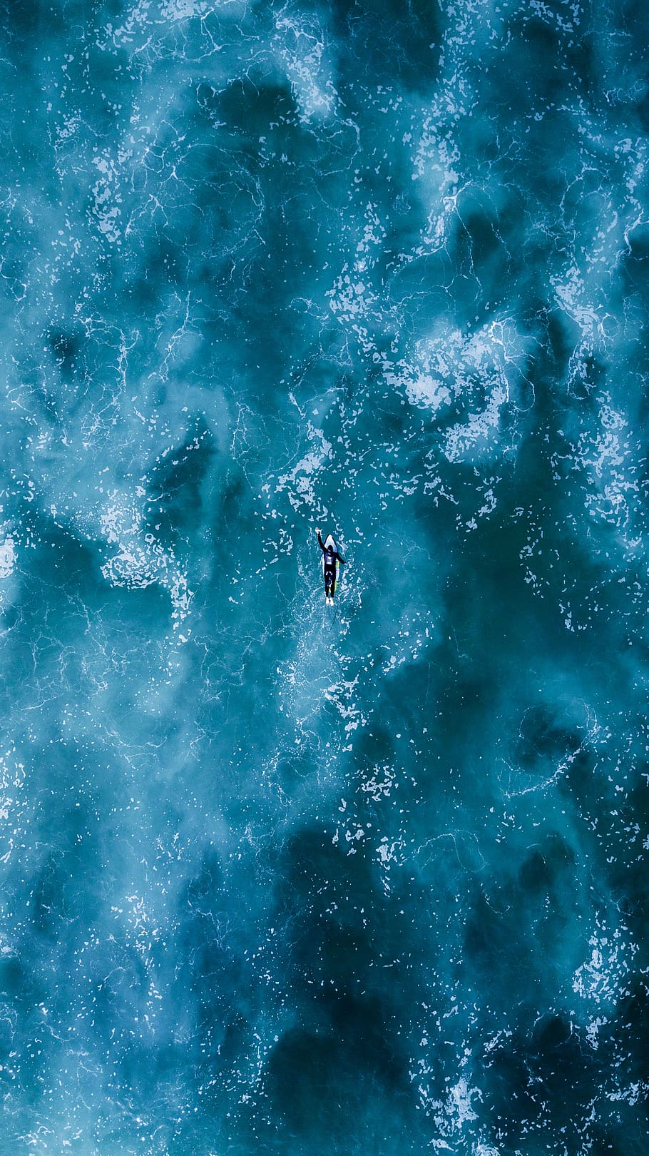 person swimming on body water, bird's eyeview photography of person surfing on body of water