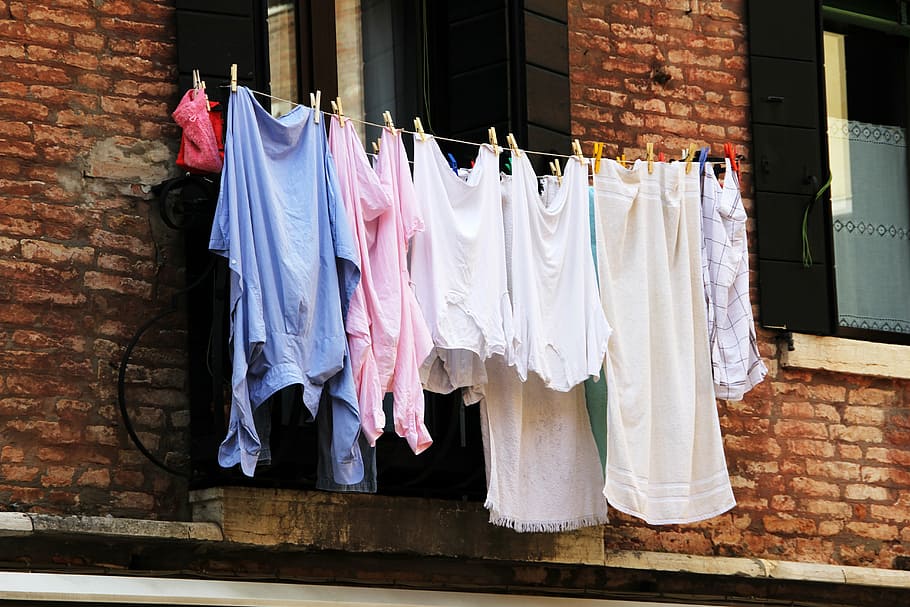 women's clothing lot hanging beside window during daytime, laundry
