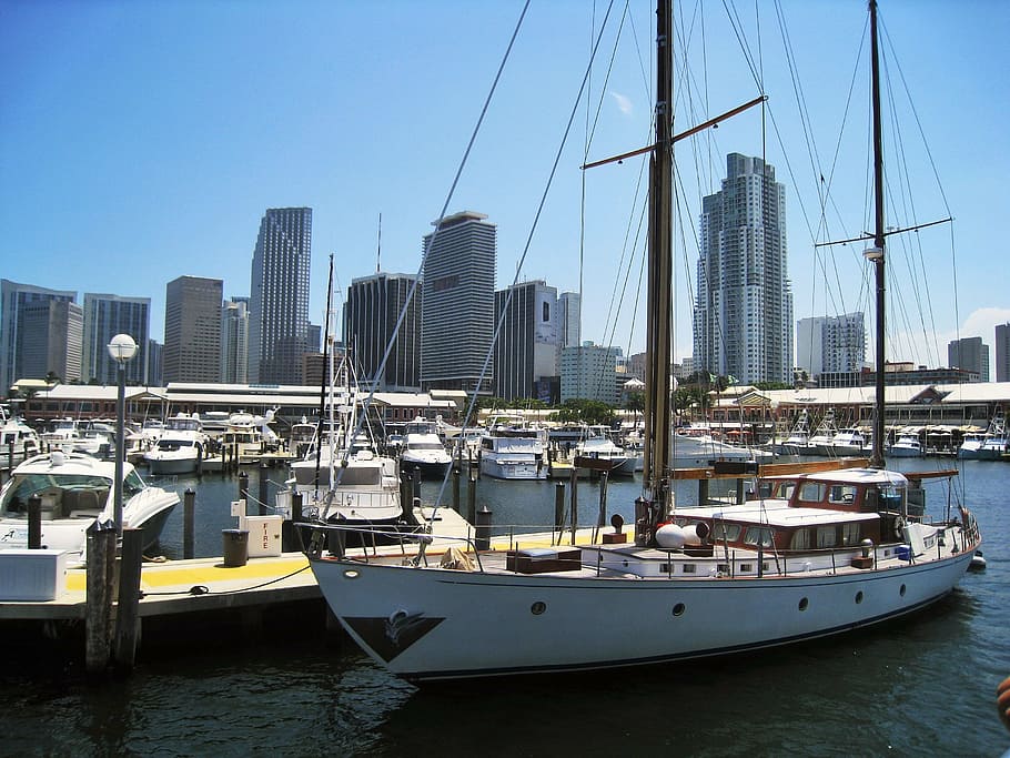 white and brown sailboat docked beside brown wooden platform