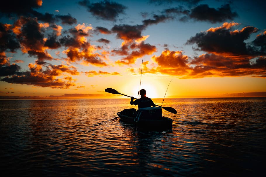 silhouette of person using boat, silhouette photography of man riding on boat during golden hour