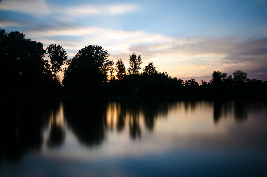 photo of mountain near body of water under blue sky, silhouette of forest near body of water at daytime HD wallpaper