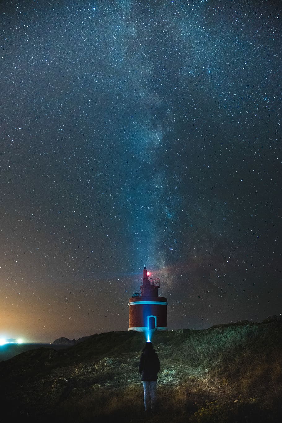 person walking towards red and white lighthouse under starry sky, girl standing near lighthouse during night time HD wallpaper