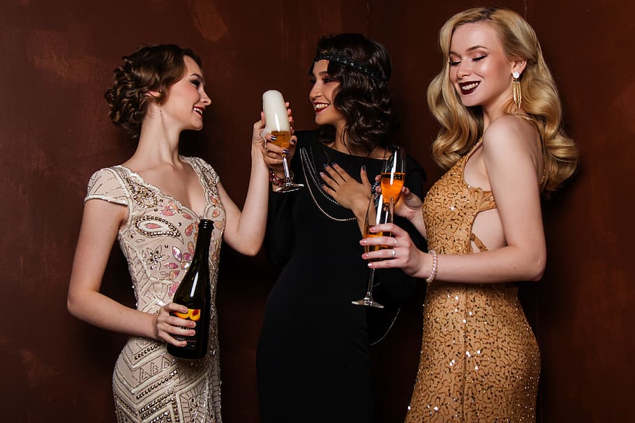 three woman holding clear wine glasses, blonde, hair, glitter